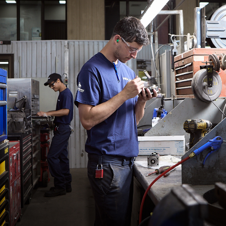 Employé portant des lunettes de protection qui répare une pièce d'équipement